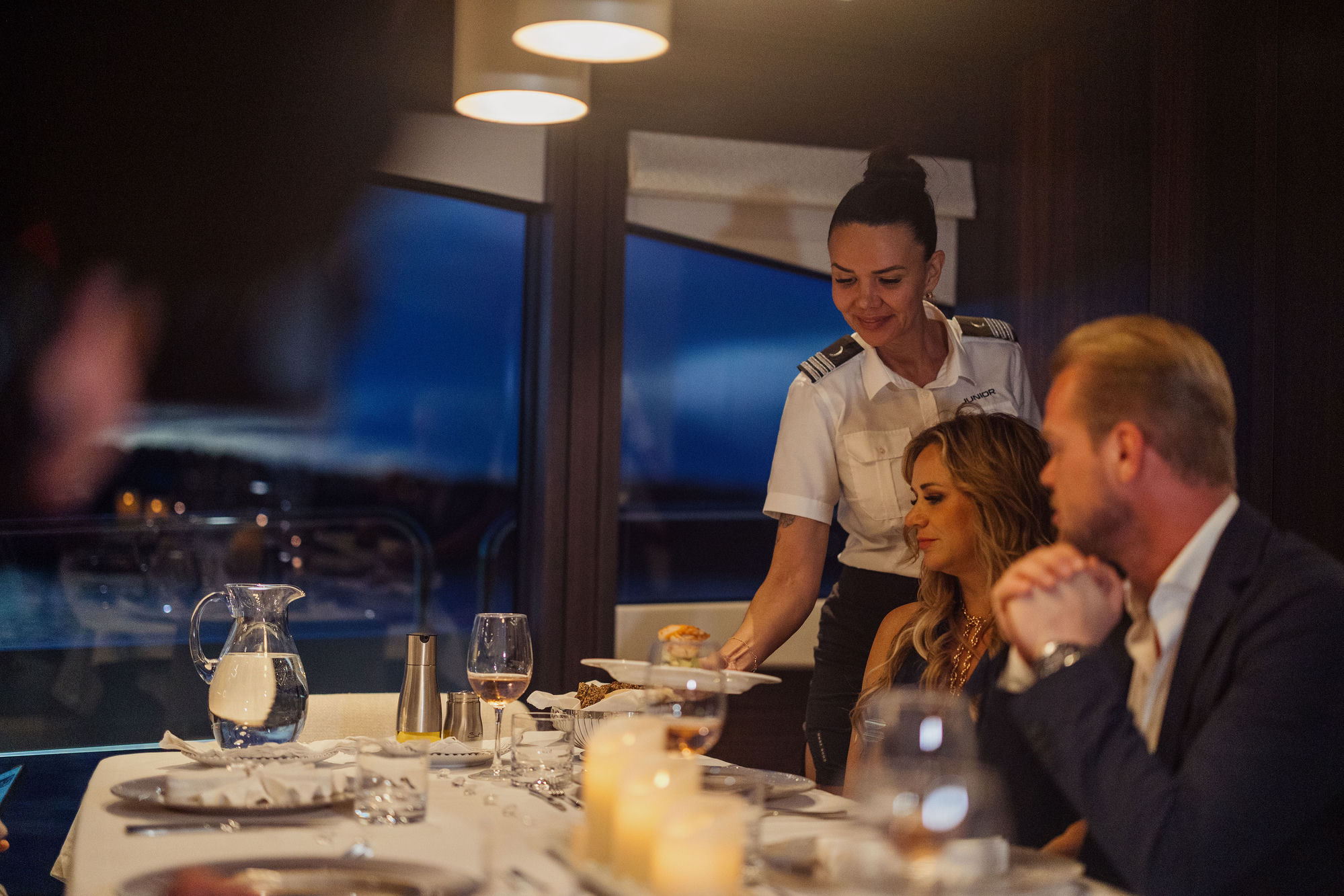 Stewardess providing attentive service aboard M/Y Junior Sunseeker 88 — luxury charter crew