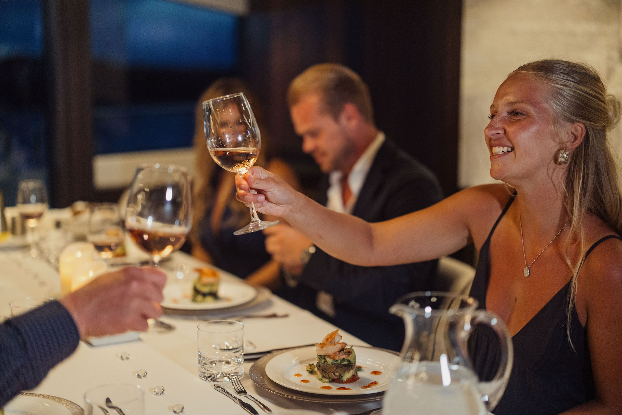 Guest raising wine glass at dinner on M/Y Junior Sunseeker 88 — charter dining